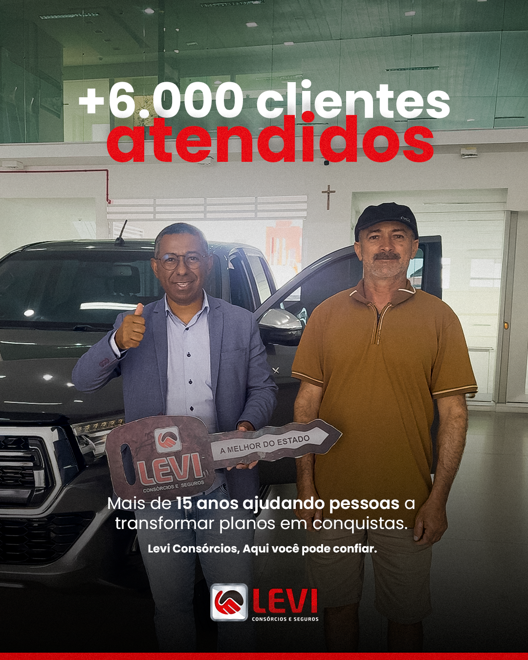Consultor Levi entregando a chave cerimonial a um cliente ao lado de uma picape